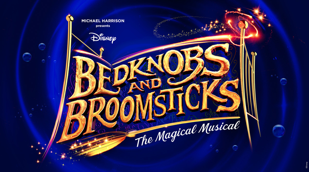 A dark blue background, in front of which is a minimalist and abstract design of a golden bed. In the foreground is the title 'Bedknobs and Broomsticks'